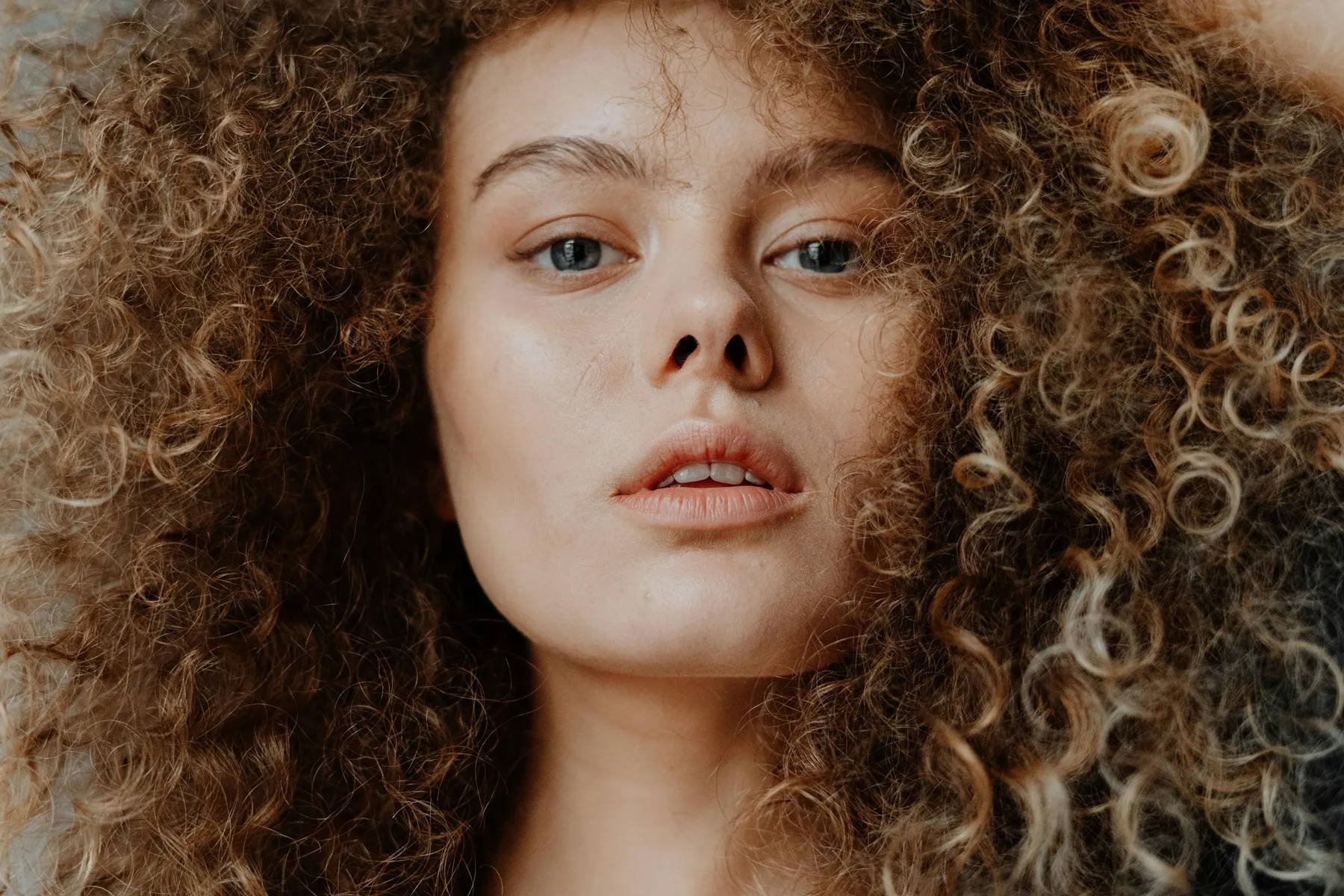 Close-up portrait of a woman with defined curly natural hair for a beginner’s guide to natural hair care.
